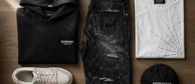 Flat-lay of streetwear pieces including heavyweight hoodie, monogram denim jeans, rhinestone tee, and sneakers on neutral wood background