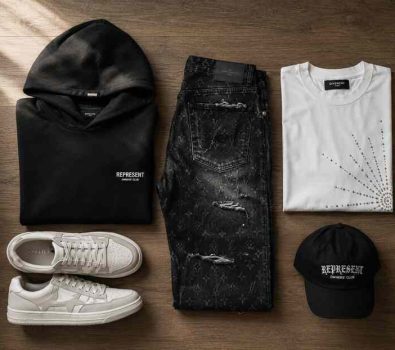 Flat-lay of streetwear pieces including heavyweight hoodie, monogram denim jeans, rhinestone tee, and sneakers on neutral wood background